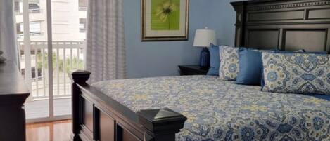 A bedroom with a bed, a nightstand, a ceiling fan, and a window with curtains.
