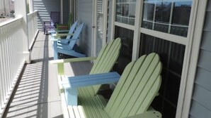 A covered porch with two green Adirondack chairs and a white railing. - 8 BED 5 BATH Condo - Perfect for Multi-Family Vacations - Summer Week Deals (North Myrtle Beach)