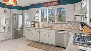 A modern kitchen with white cabinetry, stainless steel appliances, and a decorative stained glass light fixture.
