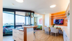 A modern kitchen with a central island, dining area with chairs, and a large window offering a city view. - Roof-top panorama suite with distant views over Vienna (Wien)