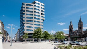 A modern building with a grid-like facade and large windows, adjacent to a historic church with twin spires. - Roof-top panorama suite with distant views over Vienna (Wien)
