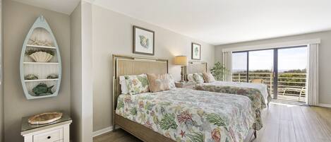 A bedroom with two beds, a nightstand, a decorative shelf with shells, and a view of the outdoors.