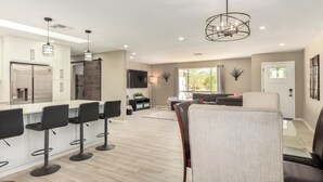 A modern kitchen with a central island, bar stools, and a dining area with a sofa and chairs. - The Valley View- Heated Pool/ Hiking/ Rooftop/ Gym/ WFH (Phoenix)