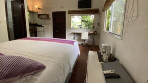 A hotel room with a bed, a desk with a laptop, a coffee maker, and a TV on the wall. - WiFi+Pool+10min 2 Surf+Nature+Private+Quiet  (La Ermita)