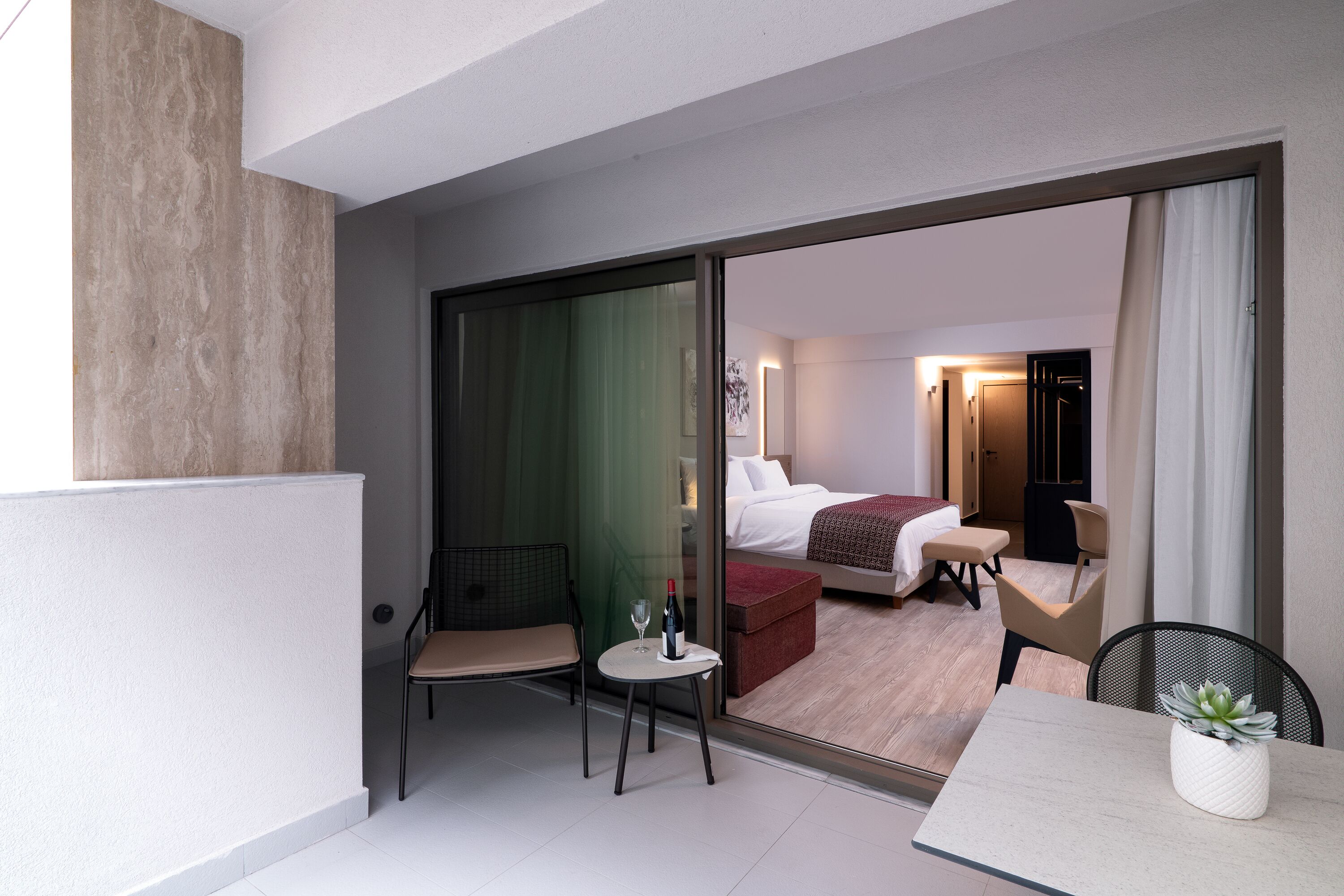 Ein modernes Hotelzimmer mit Balkon, Bett, Sitzecke und Esstisch.