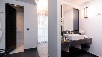 A modern bathroom with a large mirror, white sink, and dark marble countertop.