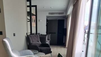 Una sala moderna con sofá, sillones y una planta grande al frente.