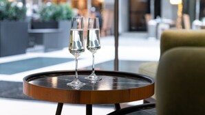 Two champagne flutes on a round table with a modern design, set in a well-lit indoor space with a view of the outdoors. - S Hotel Boutique Thessaloniki (Thessaloniki)