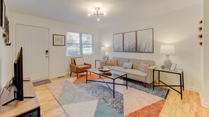 A living room with a sofa, armchair, coffee table, TV, and artwork on the walls. - Modern Renovated Apartment in the ♥️ of the City (Columbia)