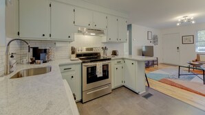 A modern kitchen with white cabinets, stainless steel appliances, and a large island. - Modern Renovated Apartment in the ♥️ of the City (Columbia)