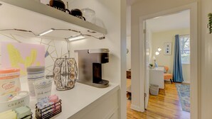 Une cuisine avec une machine à café, une tasse à café et un bocal posés sur le comptoir.
