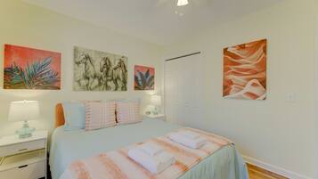 A bedroom with a bed, nightstands, a lamp, and artwork on the walls.