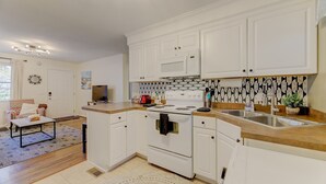 A modern kitchen with white cabinets, a built-in microwave, and a stainless steel sink. - Comfy Cozy Convenient Condo (Columbia)