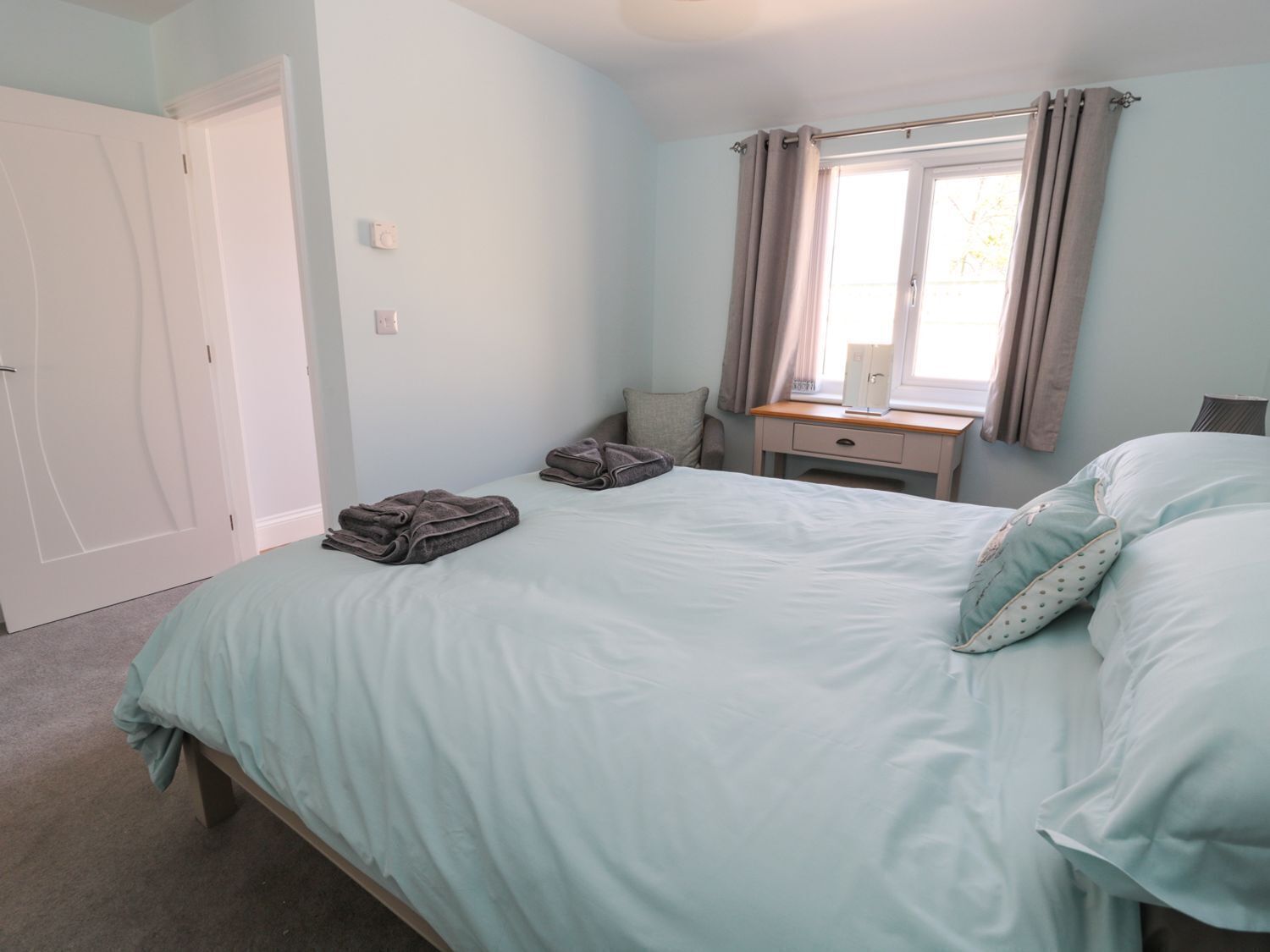 Une chambre à coucher avec un lit, une table de chevet, une fenêtre avec des rideaux et une porte.
