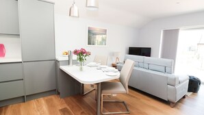 A modern kitchen with a dining area, grey cabinets, a white table, and a grey sofa. - 3 The Paddock (Chathill)