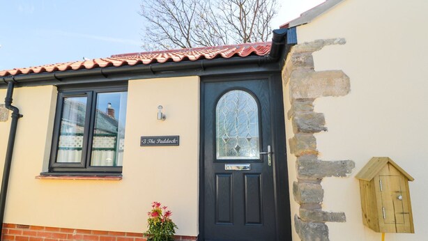 A building with a black door, a window, and a small sign reading "3 The Paddock". - 3 The Paddock (Chathill)