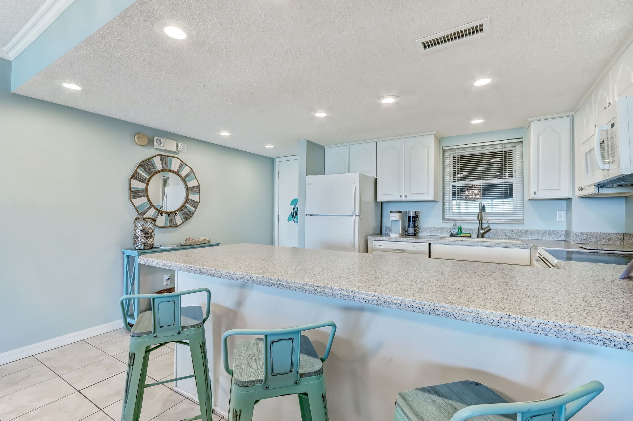 Una cocina moderna con una isla grande, taburetes de bar y un microondas.