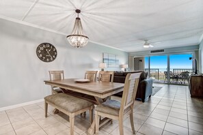 A dining area with a wooden table and chairs, a chandelier, and a clock on the wall.