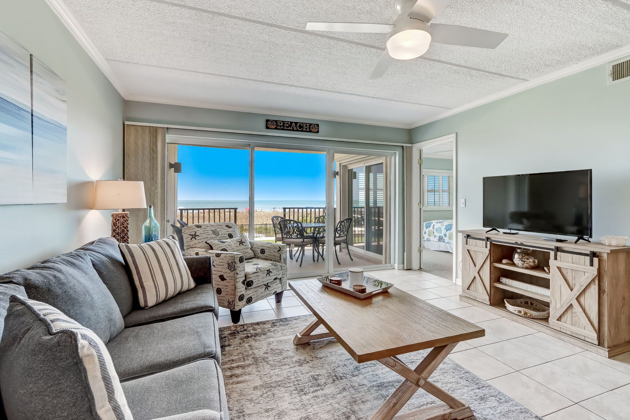 A living room with a sofa, coffee table, TV, and a sign reading "Beach".