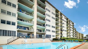Un hotel de varios pisos con piscina, balcones y cielo despejado.