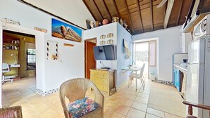 A cozy living room with a TV, a dining area, and a kitchen. - Beautiful House With Access to Pool, Tenerife, ES (San Cristóbal de La Laguna)