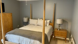A four-poster bed with a wooden frame, two bedside tables with lamps, a wooden wardrobe, and a ceiling fan. - Very Spacious, Open Floor Plan 2 Bedroom Apt.  (Gray)