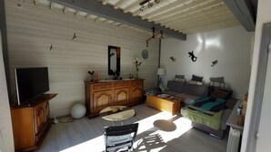 A cozy living room with a TV, wooden furniture, a sofa, a bed, and decorative wall art.
