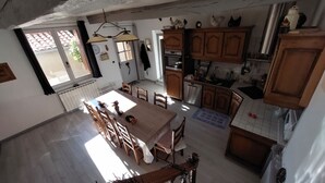 A kitchen with wooden cabinets, a dining table with chairs, and a window with curtains.