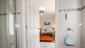 A bathroom with a shower, a towel rack, and a bed with a view of a landscape. - Awel Deg, Newport (Newport)