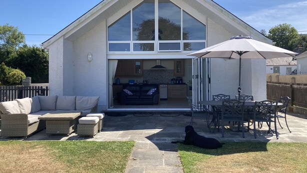 A modern house with a large patio area, outdoor seating, and a visible kitchen. - Awel Deg, Newport (Newport)