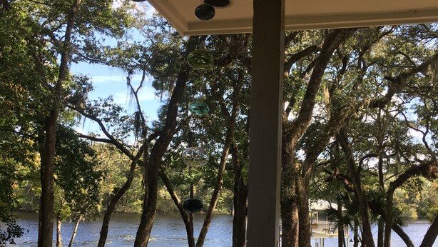 Un espace extérieur abrité, avec vue sur un lac, entouré d’arbres et doté d’un quai.