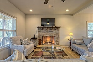 Cozy seating area with a stone fireplace, comfortable sofa, and armchairs, perfect for relaxing.