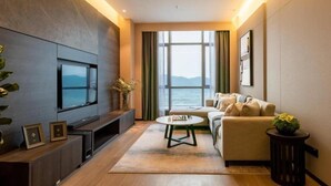 A modern living room with a large TV, a sofa, a coffee table, and a view of the sea. - Somerset Southbay Zhuhai (Zhuhai)