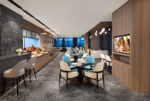 A modern dining area with a marble floor, a long counter with bar stools, and a central dining table with chairs. - Southbay Hotel Residence Zhuhai (Zhuhai)