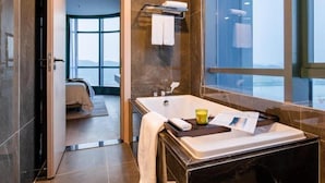A modern bathroom with a bathtub, a towel rack, and a window offering a view. - Somerset Southbay Zhuhai (Zhuhai)