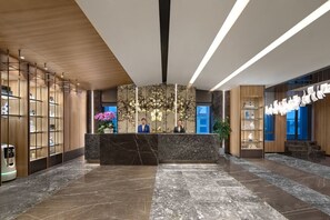 A hotel lobby with a reception desk, wooden paneling, marble flooring, and a modern chandelier. - Southbay Hotel Residence Zhuhai (Zhuhai)