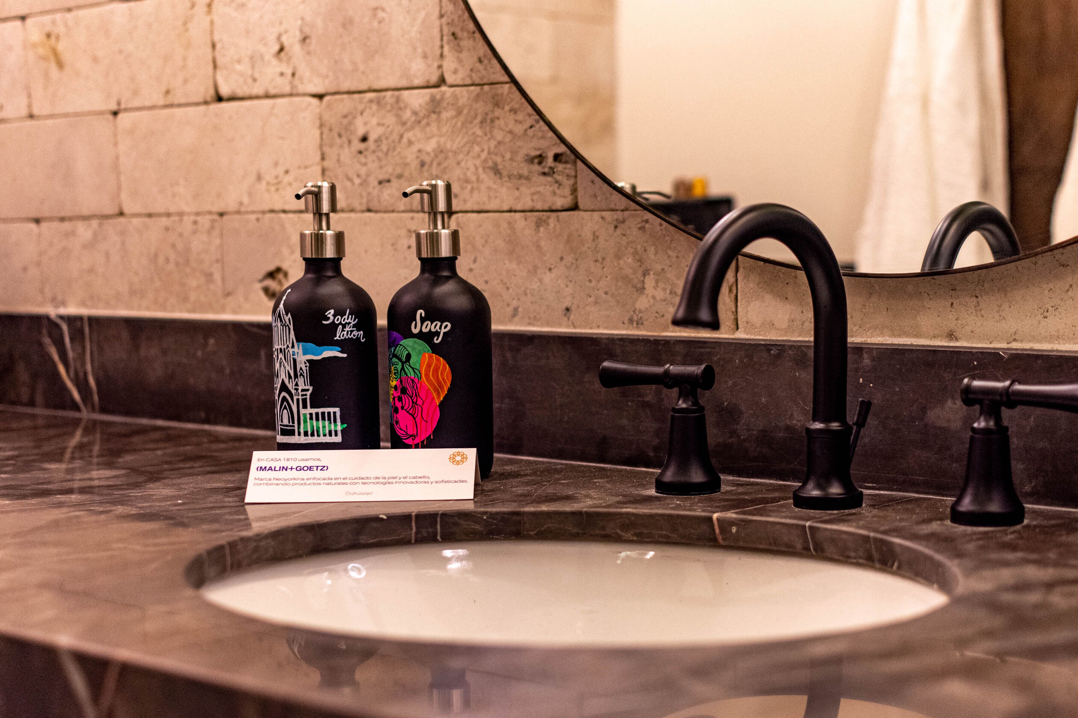 A bathroom sink with two soap dispensers and a mirror.