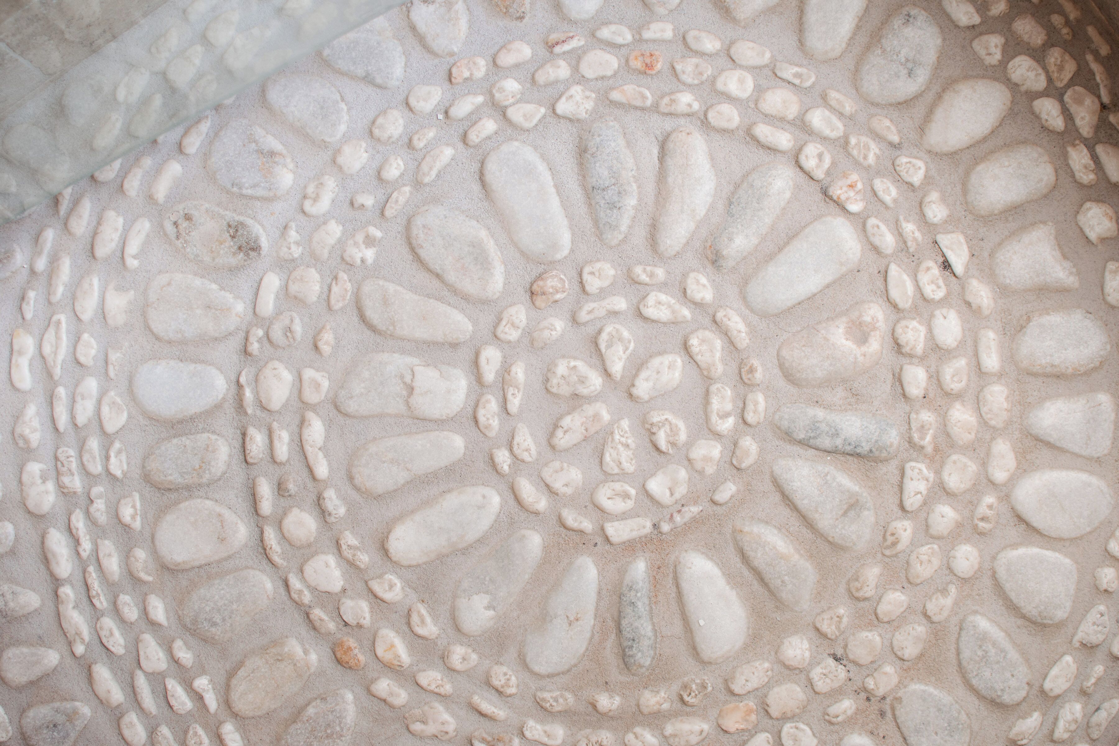 A close-up of a textured floor with a circular pattern of pebbles.