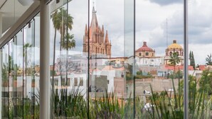 A modern interior with large windows offering views of historic buildings and a clear sky. - Casa 1810 Parque Hotel Boutique (San Miguel de Allende)