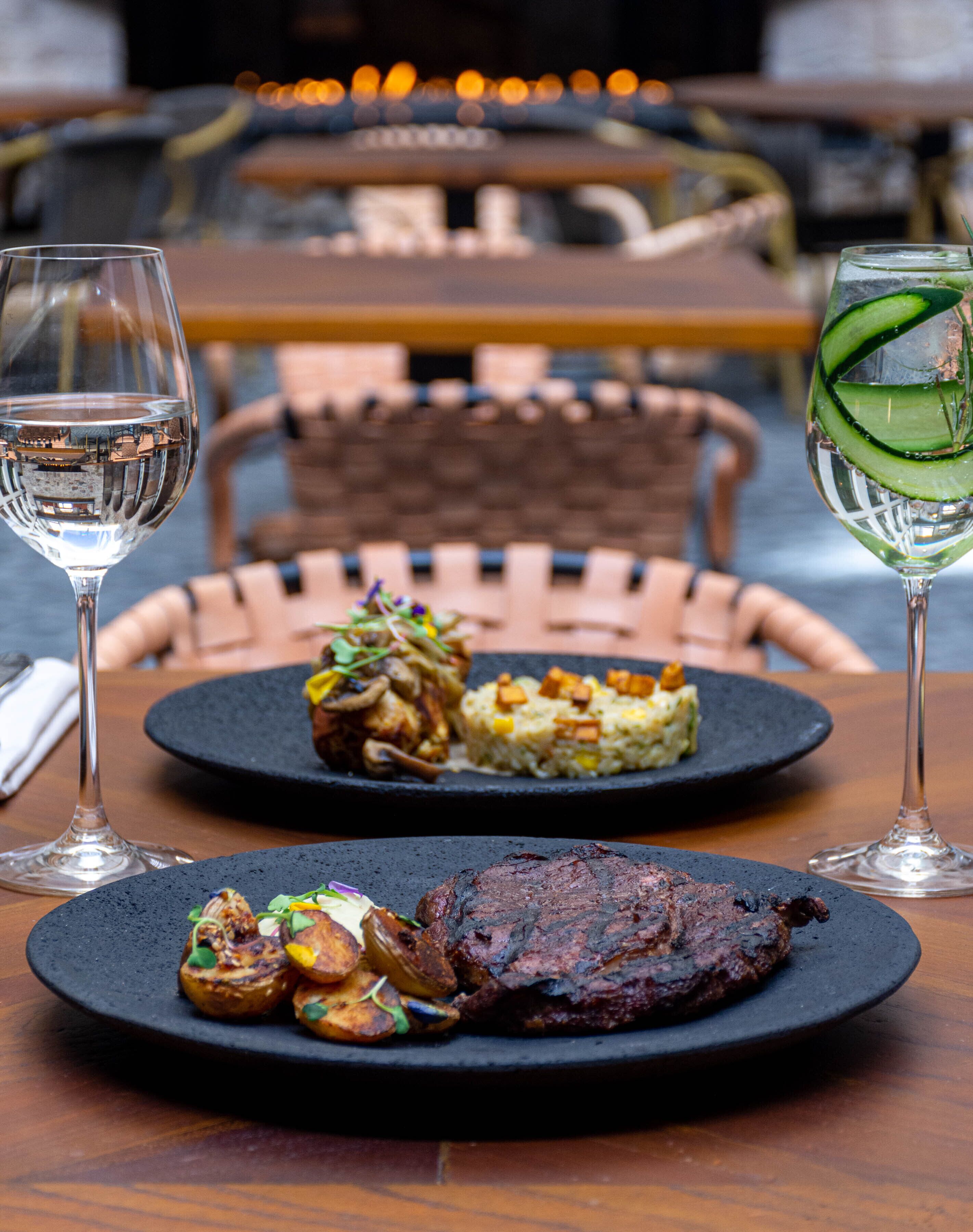 A dining table with plates of food, two glasses of water, and a chair in the background.