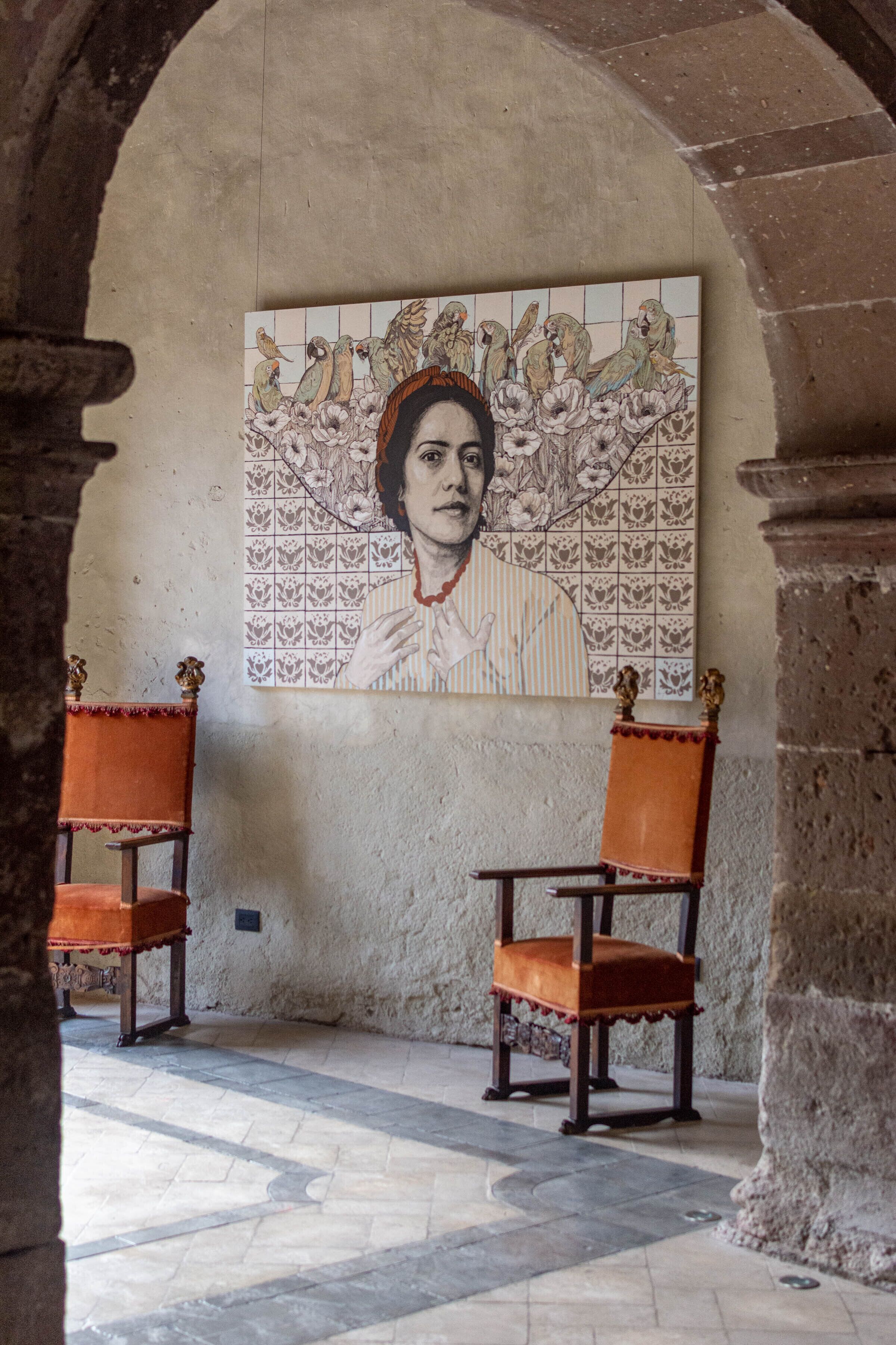 Una habitación con dos sillas de madera, un mural de azulejos en la pared y un suelo de piedra.