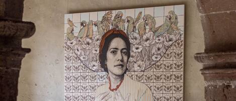 Una habitación con dos sillas de madera, un mural de azulejos en la pared y un suelo de piedra.