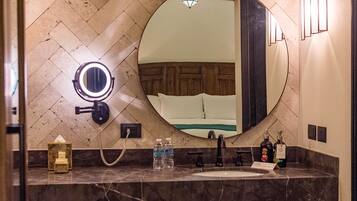 A bathroom with a round mirror, a vanity with a sink, and a towel rack.