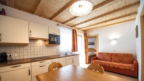 Een keuken met houten kastjes, een magnetron en een eettafel met stoelen.