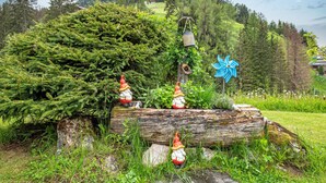 Ein Garten mit Gartenzwergen, einem Vogelhaus und einem Baumstamm.