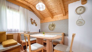 Une pièce chaleureuse avec un plafond en bois, une table ronde entourée de chaises, un canapé et une horloge au mur.