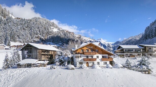 Une station de montagne enneigée, avec des bâtiments en bois, dont un chalet imposant portant une enseigne où l'on peut lire « CULAC ».