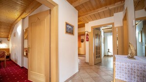 Un couloir d’hôtel avec un plafond en bois, une moquette rouge et une statue posée sur une table.
