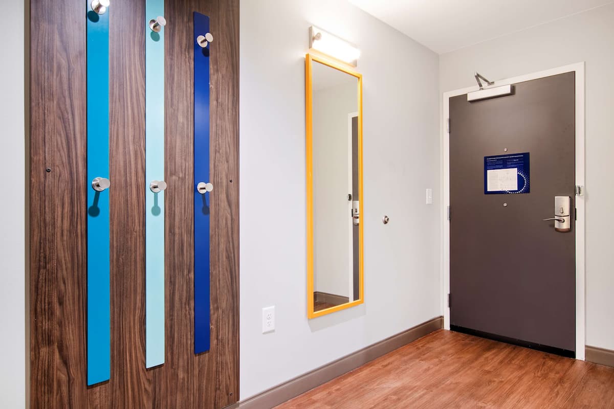 A hallway with three doors, a mirror, and a door with a sign.