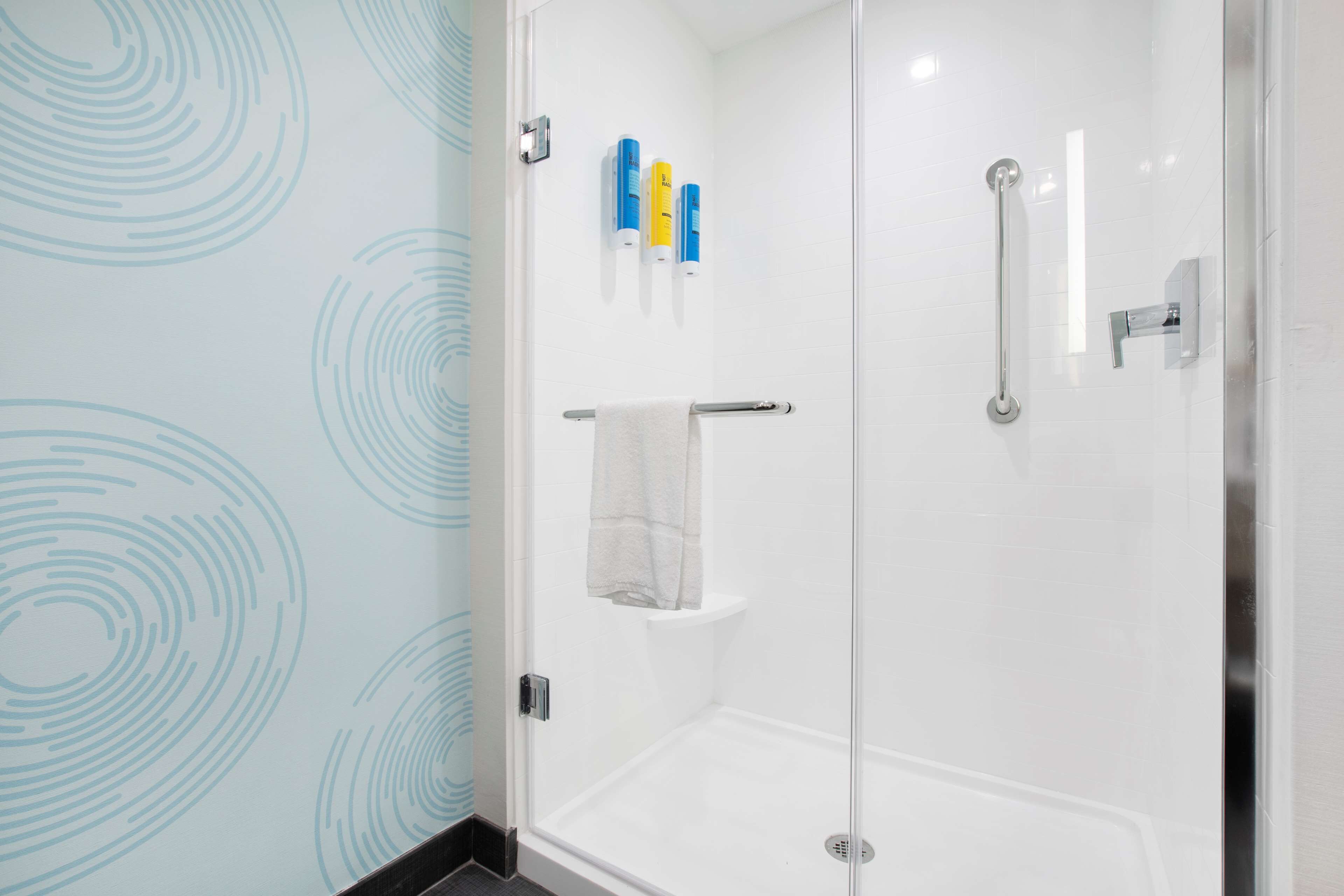 A glass-enclosed shower with a white towel rack and a glass shower door.
